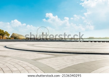 Empty square floor and playground ferris wheel with sky clouds