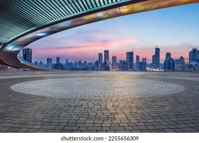 Empty square floors and bridge with city skyline at sunset in Shanghai, China.
