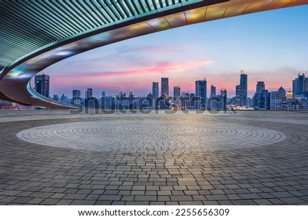 Empty square floors and bridge with city skyline at sunset in Shanghai, China.