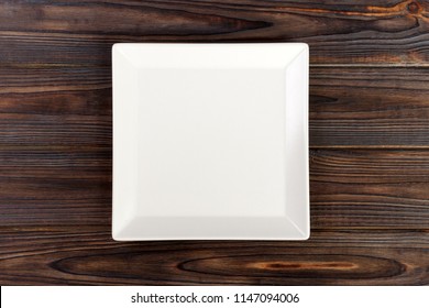 Empty Square White Plate On Wooden Table Top View.