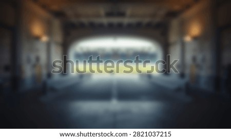 An empty stadium with rows of seats and a bright field visible through the archway. The concourse area is dark with overhead lighting.