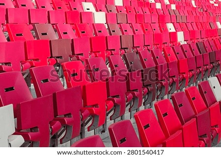 Empty stadium seats creating patterns of red and white, visualizing anticipation or post event quiet