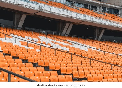 Empty stadium seats in patterned orange rows reflecting modern arena architecture.