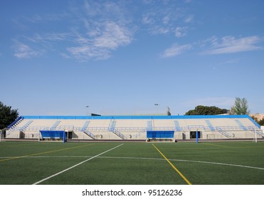 Empty Stadium Soccer Field Bleachers Dugout Under Sunny Blue Sky