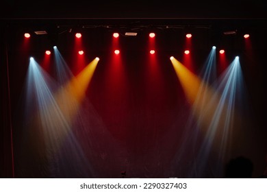 Empty stage lighting setup with red, yellow, and blue spotlights shining down, creating a dramatic atmosphere on a dark backdrop, perfect for concert or theater scenes. - Powered by Shutterstock