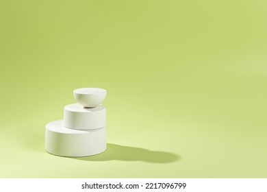 An Empty Stage With Three White Podiums Of Different Sizes On A Green Background And Shadows. Stand For Demonstration Of Models Of Cosmetic Products And Packages