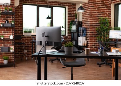 Empty Startup Office With Computer And Supplies On Desk. Nobody In Business Space Used To Work On Company Growth With Monitor And Equipment. No People In Workplace With Decorations.