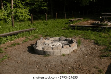 Empty stone campfire ring in a green park.
