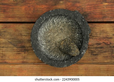Empty stone mortar with pestle on wooden table, top view