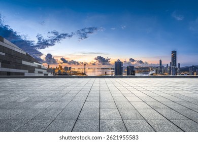 Empty stone tile floor platform overlooking the modern city skyline and waterfront buildings at dawn in Macau.