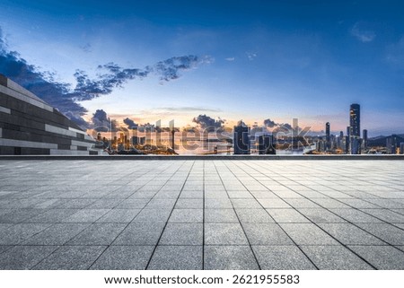 Empty stone tile floor platform overlooking the modern city skyline and waterfront buildings at dawn in Macau.