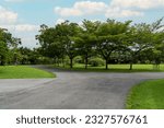 Empty street, green city park with blue sky. Pathway and beautiful trees track for running or walking and cycling relax in park on green grass field on the side. Sunlight and flare background concept