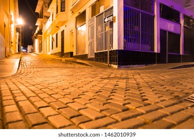 Empty Street Scene From Old San Juan Puerto Rico At Night With Buildings And Cobblestones. 