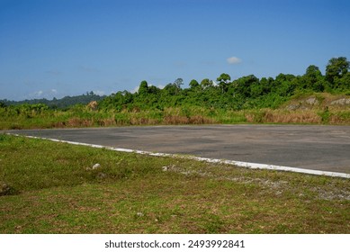 Empty streets, barren grass fields, bushes, clear blue sky. Airplane runway at a remote village in remote island  - Powered by Shutterstock