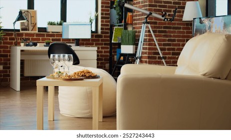 Empty stylish cozy apartment living room with charcuterie board and wine glasses on wooden table, awaiting guests to arrive for family event. House interior with leather couch and comfortable bean bag - Powered by Shutterstock