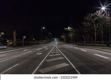 An Empty Suburban Night Scape Of A Street Lit By Pale Street Lamps And Trees And Small Houses In Copenhagen, Denmark