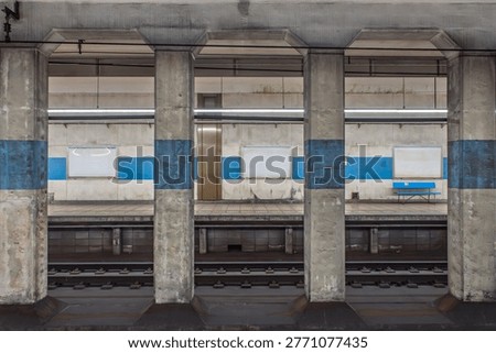 Empty subway station platform with concrete pillars and blue stripes, underground railway in Japan.