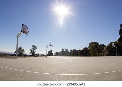 Empty sunlit basketball court in city park on hot sunny day under blue zenith sky. Bright sun in the sky. Sports, lifestyle, leisure activity concept - Shutterstock ID 2234860241