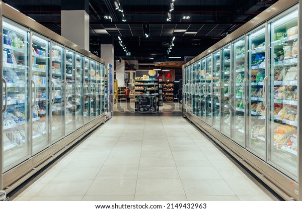 Empty supermarket aisle with freezers showcases\
with different products