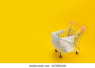  Empty Supermarket Cart In Medical Mask On Yellow Background, With No One, With Space For Text On The Left Side. 