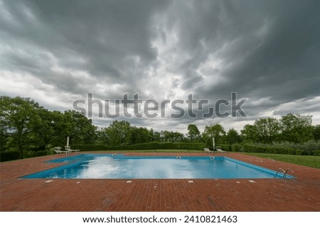 Empty swimming pool with storm clouds implying disappointment or ruined holiday.