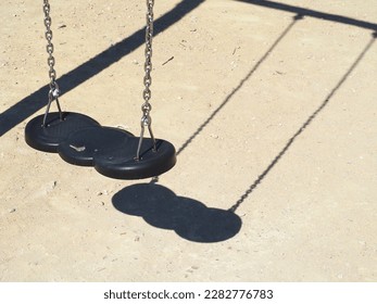 Empty swing on a bright sunny day. Shadow on the ground. - Powered by Shutterstock