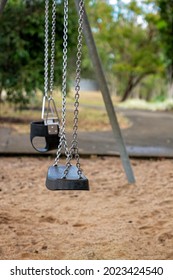 An Empty Swing Set On A Chain In An Outdoor Playground