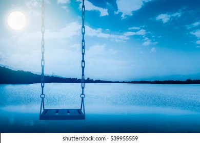 Empty Swing Set With Sea And Sky At  Full Moon Night Background,feel Sad Or Lonely Concept