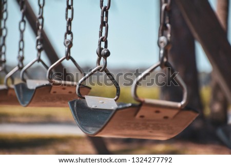 Empty swings in a playground with a soft blurred background and warm vintage tones evoke childhood memories and loneliness.