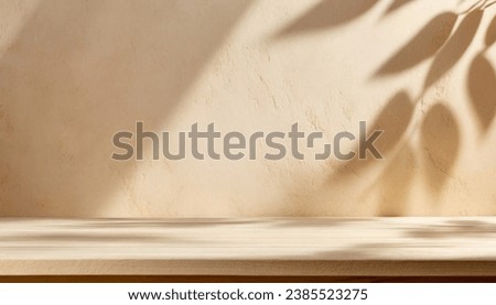 Empty table against beige textured wall background. Composition with glossy leaves  on the wall.