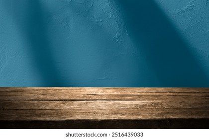 Empty table close up on blue wall texture background with shadows on background. Mockup for presentation, product branding, cosmetics, food or jewelry to showcase your product.