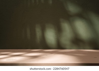 Empty table and darkgreen wall. Table with sun reflections and leaves shadows on beige wall. Background with bokeh for product presentation.Mock up for presentation, branding products, cosmetics food  - Shutterstock ID 2284760547