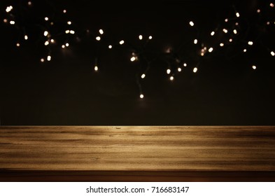 Empty table in front of black and gold glitter garland lights background. For product display montage