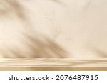 Empty table on beige texture wall background. Composition with monstera leaves shadow on the wall. Mock up for presentation, branding products, cosmetics food or jewellery.