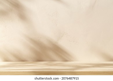 Empty table on beige texture wall background. Composition with monstera leaves shadow on the wall. Mock up for presentation, branding products, cosmetics food or jewellery.