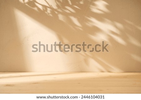 Empty table on bright brown wall background. Composition with geometrical window shadow on the wall and wooden desk. Mock up for presentation, branding products, cosmetics, food or jewelry.