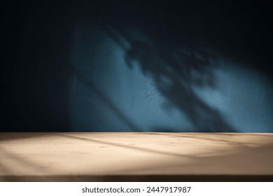 Empty table on dark blue texture wall background. Composition with organic shadow on the wall and light reflections. Mock up for presentation, branding products, cosmetics food or jewelry.