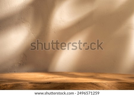 Empty table on stucco beige wall background. Mock up for presentation, branding products, cosmetics, food or jewellery. Wood board on bright brown background. Composition with beautifull shadows