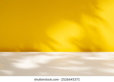  Empty table on yellow wall background. Composition with abstract light and leaves shadows. Mock up for branding products presentation.