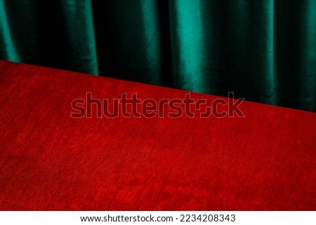 Empty table with red cloth and green draped velvet curtains. Template for advertising, presentation, cosmetic products. Mockup, background.