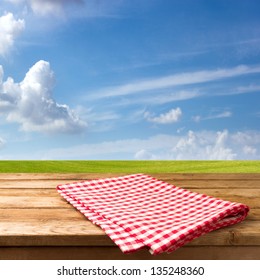 Empty table with tablecloth over beautiful meadow and blue sky