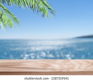 Empty table top under palm leaves and blurred sparkling sea at the background. Place for your product or brand name display. - Shutterstock ID 2187319541