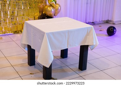 An empty table with a white tablecloth on a holiday.