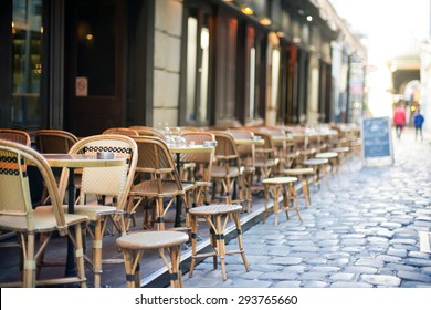 Empty tables in between dining hours along a Paris cobblestone alley