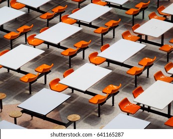 Empty Tables Chairs Set In Rows Of Large University School Canteen Lunch Room Easy Clean Industrial Style Design White Top Plate Orange Plastic Seats On Fixed Metal Frame Construction Top View  