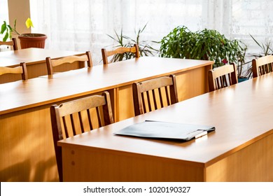 Empty Tables In The Classroom. On The Table Is A Folder