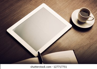 empty tablet pc and a coffee and notebook with pen on the office desk - Powered by Shutterstock