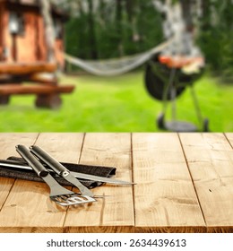 Empty Tabletop with Backyard Grill in Background – Outdoor Spring and Summer BBQ Concept. Copy space for product placement.