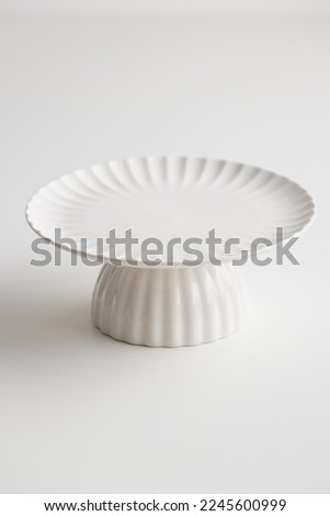Empty tableware - white plate cakestand on white table as a background for a dessert vertical photo with a copy space, food mokup