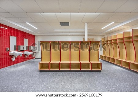 Empty team locker, changing room with traditional open wooden lockers with a red trim.